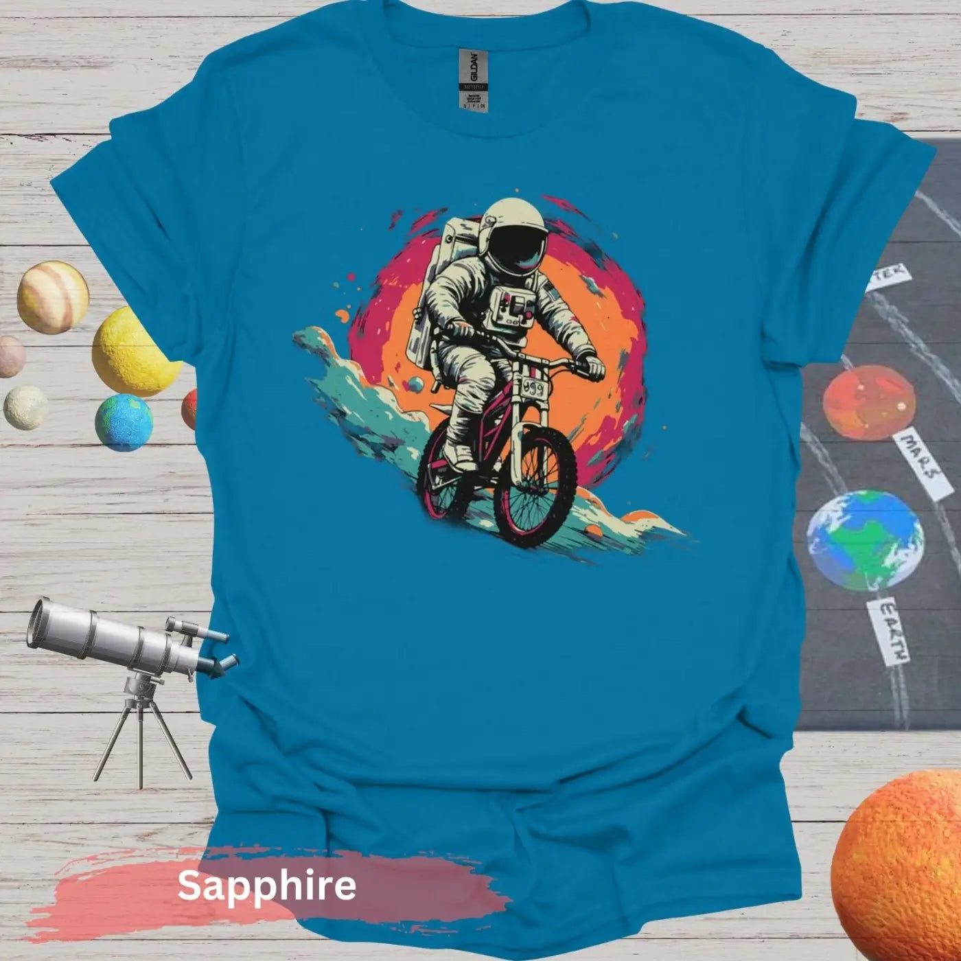 Cosmic Cyclist: Astronaut Biking Adventure T-Shirt - S - Unisex / Sapphire - Physical Item