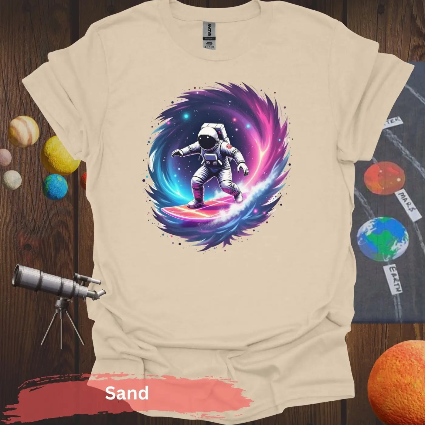 Cosmic Wave Rider – Astronaut Surfing Space Design T-shirt - S / Sand - Physical Item